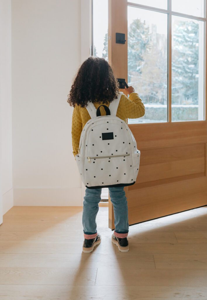 young child with a backpack opening a door, identity and anxiety Evoke Wellness NC