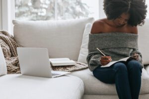woman sitting on a couch writing identity and anxiety Evoke Wellness NC