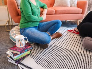 two women sitting on the floor talking in a therapy session, stack of books and a coffee mug nearby, helping teens learn to manage anger and aggression blog from Evoke Wellness, Wilmington, NC